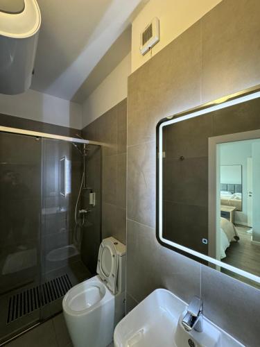 Un baño con lavabo, inodoro y espejo. en AVENUE Apartment 01 Tirana, en Tirana
