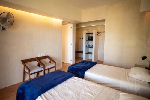 a bedroom with two beds and a chair in it at 97985 Stunning beachfront Suites Wi-Fi East of Progreso in Chicxulub