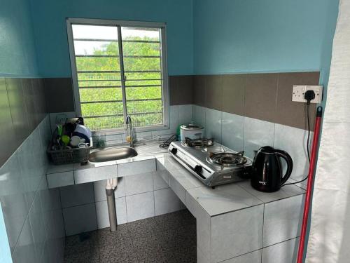 a kitchen with a stove and a sink and a window at Valai Kudat Homestay in Kudat