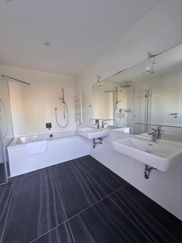 a large bathroom with two sinks and two mirrors at Villa Parndorf Lake 1 next to Outlet in Parndorf