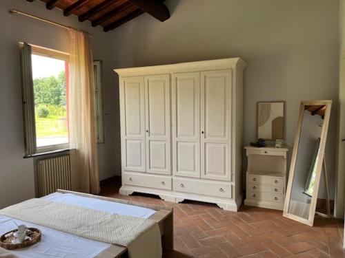 a bedroom with a large white cabinet and a mirror at My Tuscany Relais in Altopascio