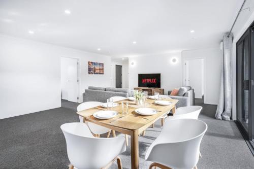 a dining room with a table and white chairs at King Bed, Modern and Peaceful - By KOSH BNB in Hamilton