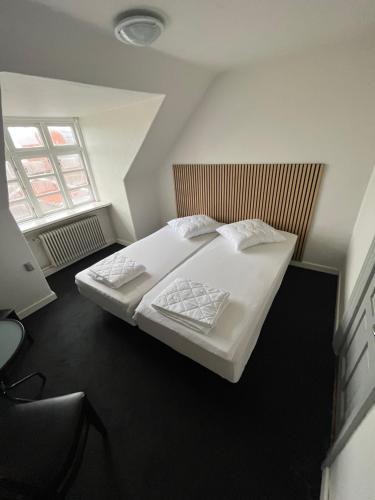 a bedroom with a bed with white sheets and pillows at Folsted - Værelse 201 fri parkering in Bindslev