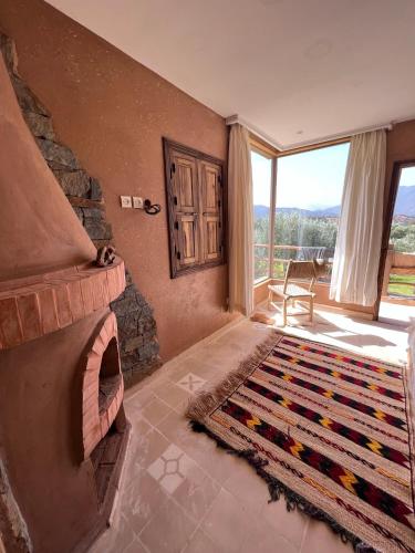 a living room with a stone fireplace and a rug at Bin Jbal Resort in Ouirgane