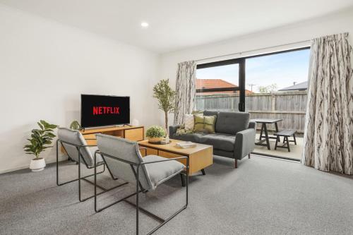 a living room with a couch and a tv at Modern and Central with 2 Ensuites -By KOSH BNB in Hamilton