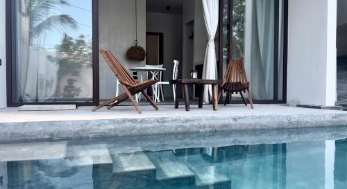 two chairs and a table next to a swimming pool at COCCOLOBA in Holbox Island