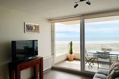 a living room with a sliding glass door with a view of the ocean at Smart Host Rentals - Vive la energía de La Serena in La Serena
