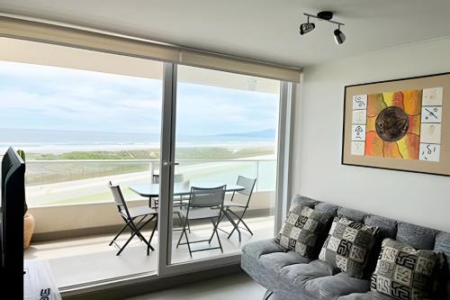 a living room with a table and chairs and a large window at Smart Host Rentals - Vive la energía de La Serena in La Serena