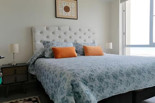 a bedroom with a bed with a blue comforter and orange pillows at Smart Host Rentals - Vive la energía de La Serena in La Serena