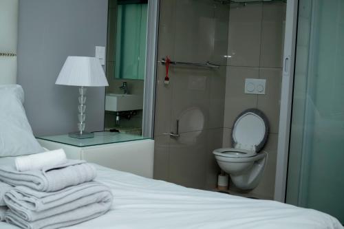 a bedroom with a toilet and a bed with towels at Freedom Plaza serviced apartments in Windhoek