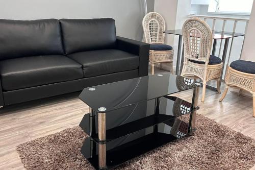 a living room with a black couch and a glass table at Chadwich Heights in Bromsgrove