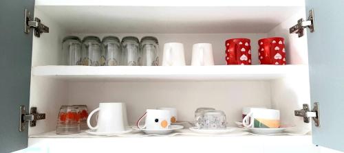 a shelf with cups and vases in a cabinet at Rutcha homestay Betong รัชชา โฮมสเตย์ เบตง in Betong