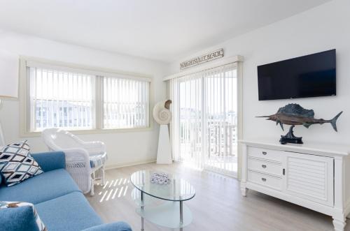 a living room with a blue couch and a flat screen tv at Shearin by Bryant Real Estate in Wrightsville Beach