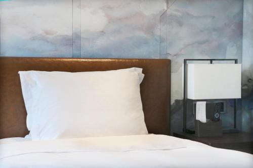 a bed with a white pillow next to a lamp at Crowne Plaza Chengdu Wenjiang by IHG in Chengdu