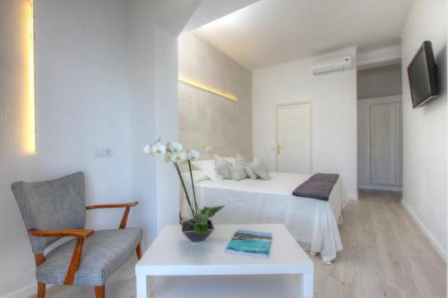 a room with two beds and a chair and a table at Hotel Brismar in Port d'Andratx