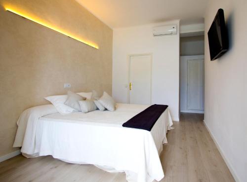 a bedroom with a white bed and a television at Hotel Brismar in Port d'Andratx