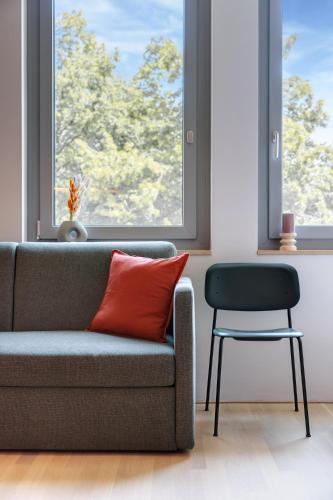 a couch and a chair in a room with a window at DEIN APART München in Munich