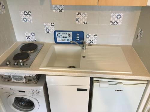 une cuisine avec un évier et une cuisinière dans l'établissement Charmant Studio vue Port, à Courseulles-sur-Mer