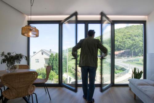 a man looking out the window of a living room at Casa Tome A Teixeira - Ribeira Sacra in Teixeira