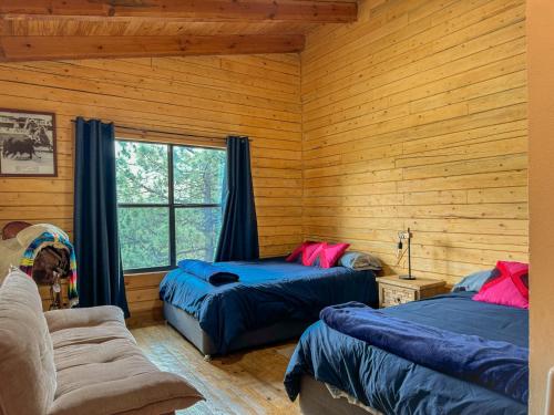 two beds in a room with wooden walls and a window at Cabaña Ohana in Mesa de las Tablas