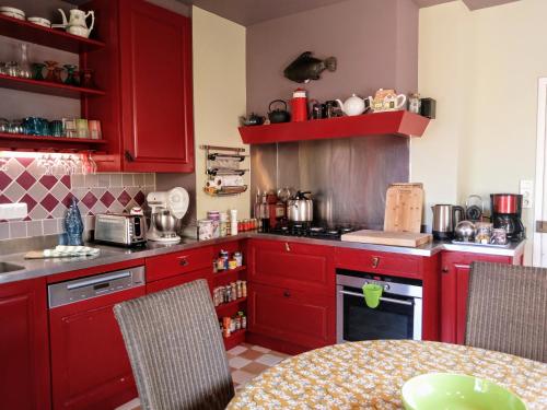 - une cuisine avec des placards rouges et une table dans l'établissement Maison de charme classée 4 étoiles centre ville vannes Garage WIFI, à Vannes