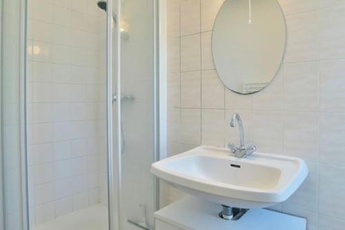 une salle de bain blanche avec un lavabo et une douche dans l'établissement Séjour Bucolique Sur les Bords de Rance, à Pleudihen-sur-Rance