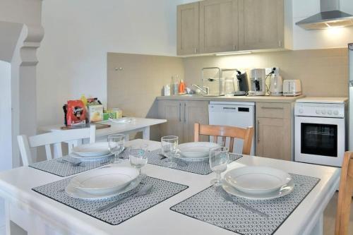 une cuisine avec une table avec des assiettes et des verres dessus dans l'établissement Séjour Bucolique Sur les Bords de Rance, à Pleudihen-sur-Rance