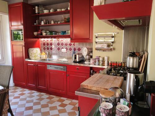 La cuisine est équipée de placards rouges et d'un four avec plaques de cuisson. dans l'établissement Maison de charme classée 4 étoiles centre ville vannes Garage WIFI, à Vannes
