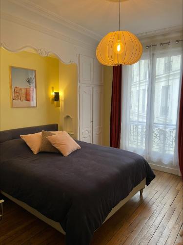 une chambre avec un grand lit et un lustre dans l'établissement Spatious Charming Parisian flat (central, Republique place, Le Marais), à Paris