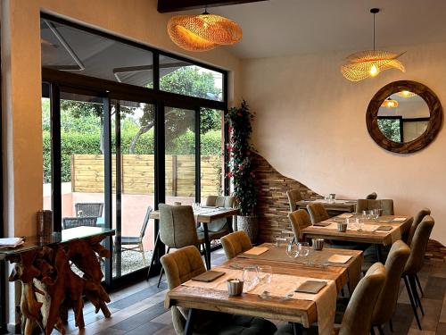 un ristorante con tavoli e sedie in legno e uno specchio di Le Clos des Arbousiers a Linguizzetta