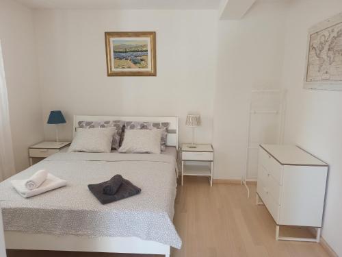 a white bedroom with a bed with towels on it at Olive Tree Apartment Zečevo in Rogoznica