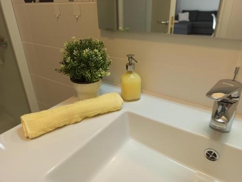 a bathroom sink with a yellow towel and a plant at Olive Tree Apartment Zečevo in Rogoznica