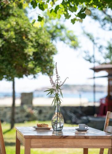 a table with a glass vase with a plant in it at Akasti Slow Living in Paralia Sikias