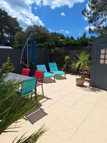 a patio with four chairs and an umbrella at Maison 4/6 personnes de 50 m² in Les Mathes