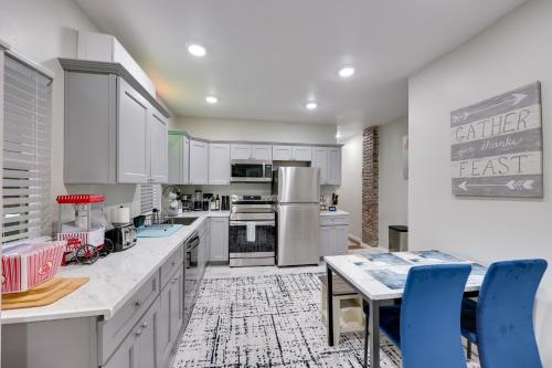 a kitchen with white cabinets and a table and blue chairs at Hot Springs Home with Yard, Walk to Bathhouse Row! in Hot Springs