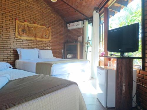 a bedroom with two beds and a flat screen tv at Pousada Alfa e Ômega in Alto Paraíso de Goiás