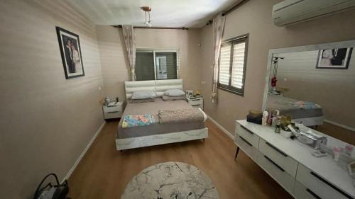 a bedroom with a bed and a sink and a mirror at קוט'ג 6 חדרים שלווה תבורית in Kefar Tavor