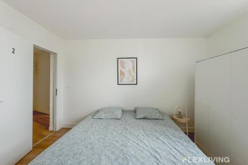 - une chambre blanche avec un lit et une couverture bleue dans l'établissement Flexliving - Room - Henri Sellier - Suresnes 92, à Suresnes