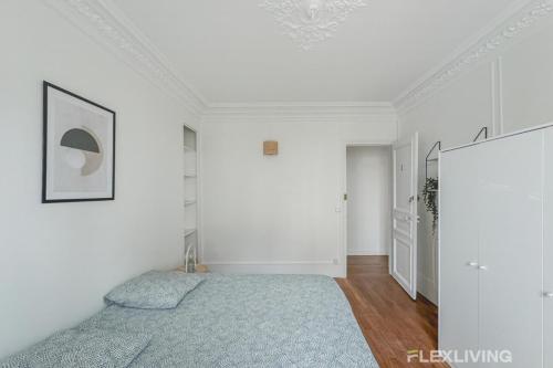 - une chambre avec des murs blancs et un lit avec une couverture bleue dans l'établissement Flexliving - Room - Henri Sellier - Suresnes 92, à Suresnes