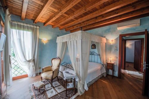 a bedroom with a canopy bed and a chair at B&B VILLA MELOGRANO PONTOGLIo in Pontoglio