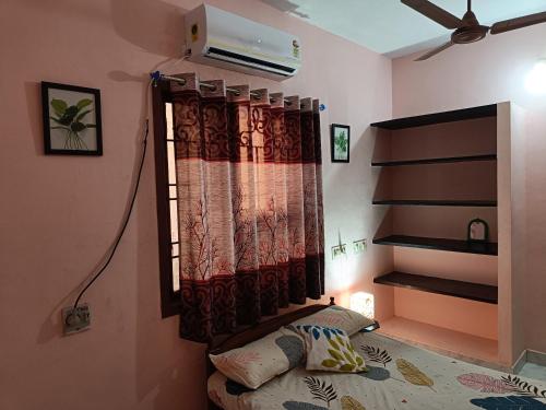 a bedroom with a bed and a window with a curtain at Rest and Relax Homestay in Puducherry