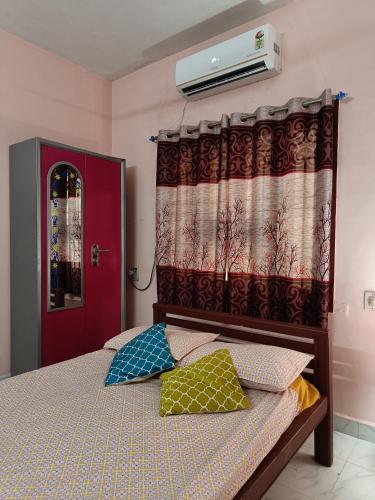 a bedroom with a bed with two pillows and a red door at Rest and Relax Homestay in Puducherry