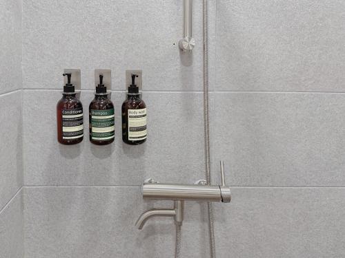 three bottles of soap on a wall in a shower at 4 bed 3 room near Gimpo airport in Seoul