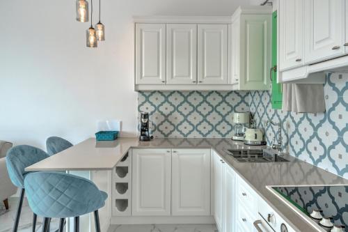 a kitchen with white cabinets and blue accents at Yani La Scala Luxury Villas in Lefkos Karpathou