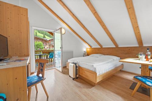 a bedroom with a bed and a desk and a window at Aparthotel Princess in Canazei