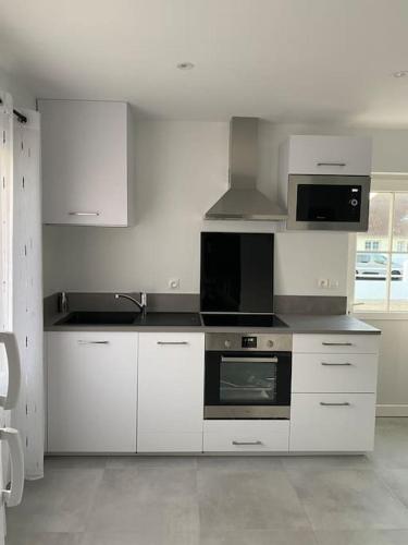 une cuisine avec des armoires blanches et un four à plaques de cuisson dans l'établissement Maison de vacances en bord de mer Gold Beach, à Asnelles