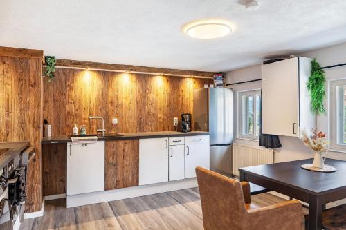 a kitchen with wood paneling and a table and a kitchen with white cabinets at Feichtenhäusl app 2 in Westendorf
