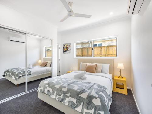 ein Schlafzimmer mit zwei Betten und einem Spiegel in der Unterkunft Brand New Comfy Home 4Bedroom designer furniture in Springfield Lakes