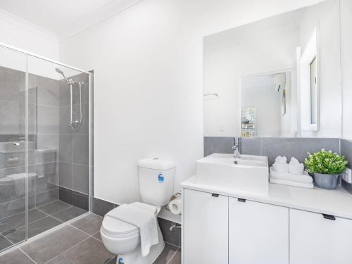 ein weißes Badezimmer mit Toilette und Dusche in der Unterkunft Brand New Comfy Home 4Bedroom designer furniture in Springfield Lakes