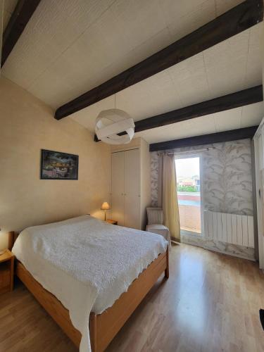 une chambre avec un lit et une grande fenêtre dans l'établissement VILLA AUX CAPELLANS SUR LA MARINA POUR 4 PERSONNES - vue Marina - Parking - plage à 5 min à pied, à Saint-Cyprien